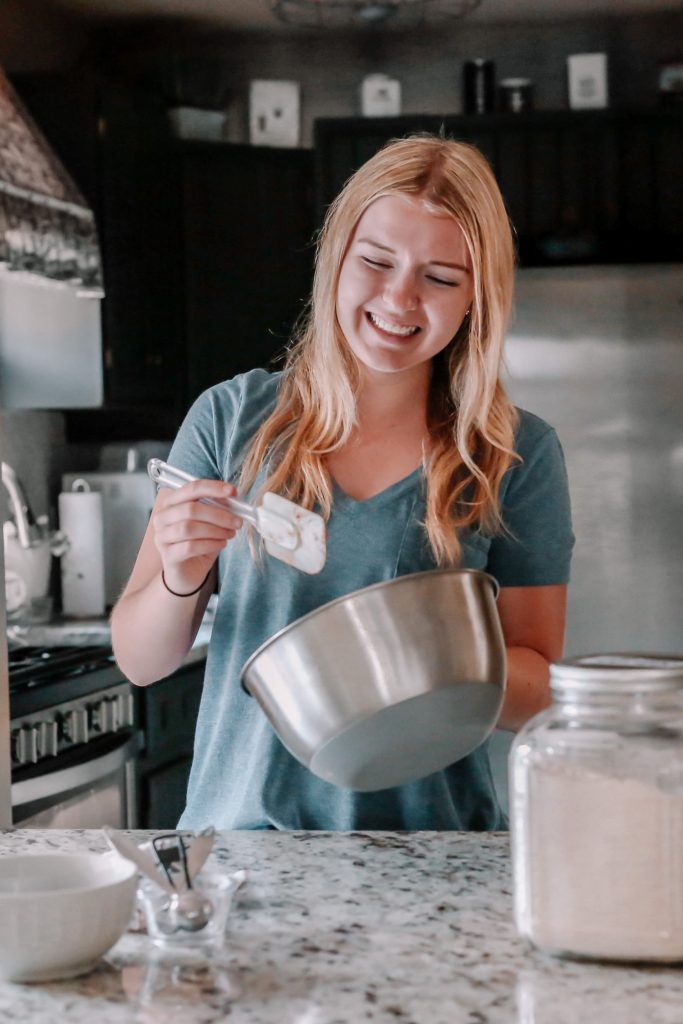 a picture of samantha from savor the spoonful, smiling and holding a mixing bowl and a spatula