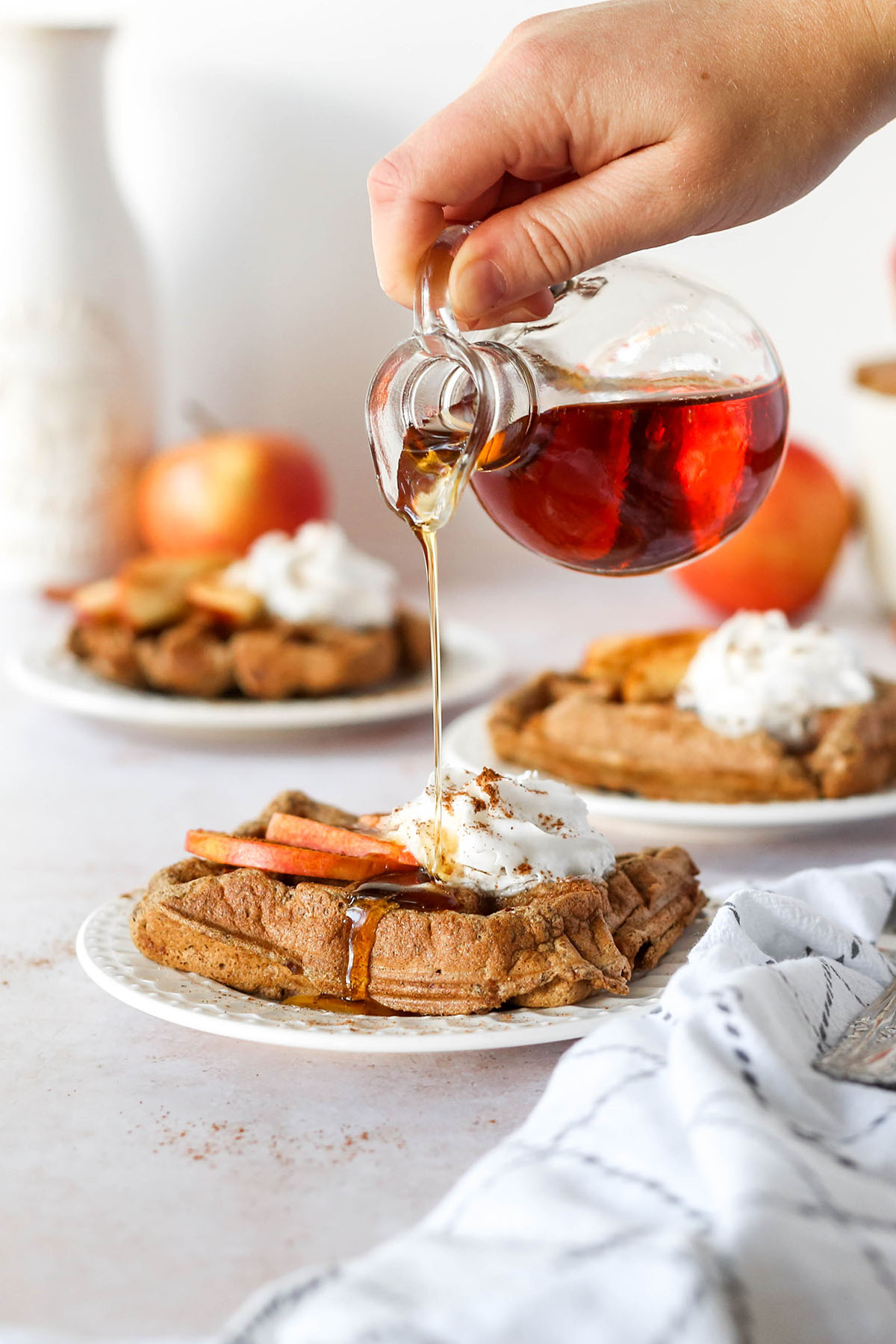 syrup being poured on top of the healthy cinnamon apple waffles