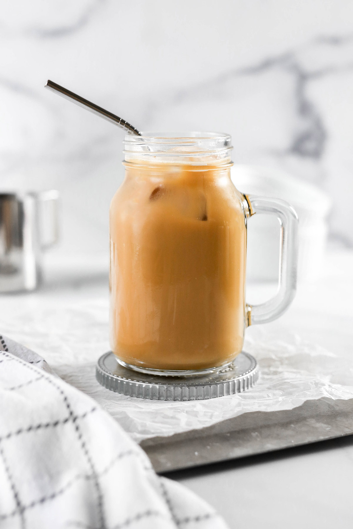 a creamy iced almond milk latte in a mason jar with a straw