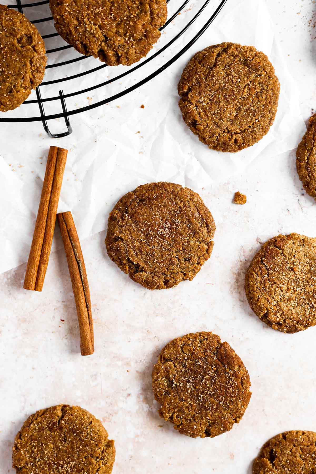 multiple molasses cookies on the table with cinnamon sticks around