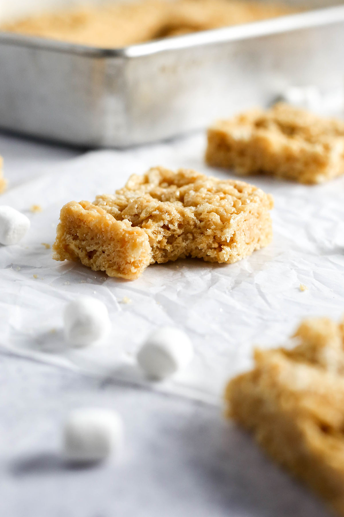 a rice krispie treat on parchment paper with a bite missing from the corner