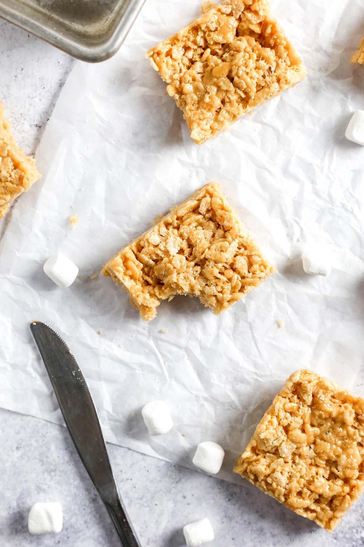 a peanut butter rice krispie treat on a grey table with a bite missing