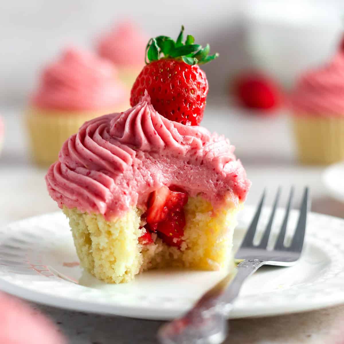 a strawberry filled cupcake with strawberry filling and pink strawberry buttercream frosting