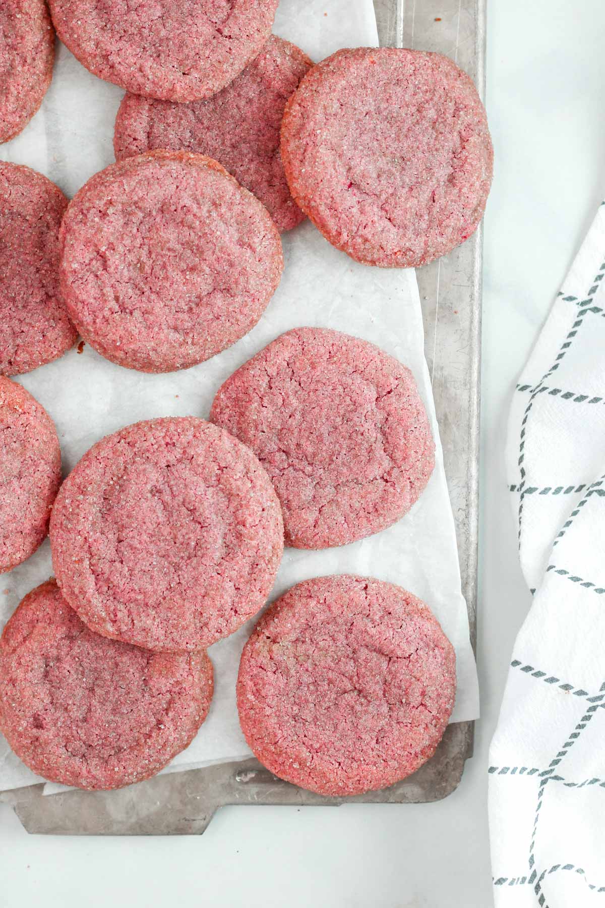 multiple sugar cookies on a baking sheet lined with parchment paper.