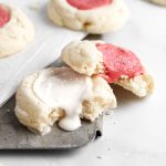 two thumbprint cookies with icing with a bite missing from each cookie.